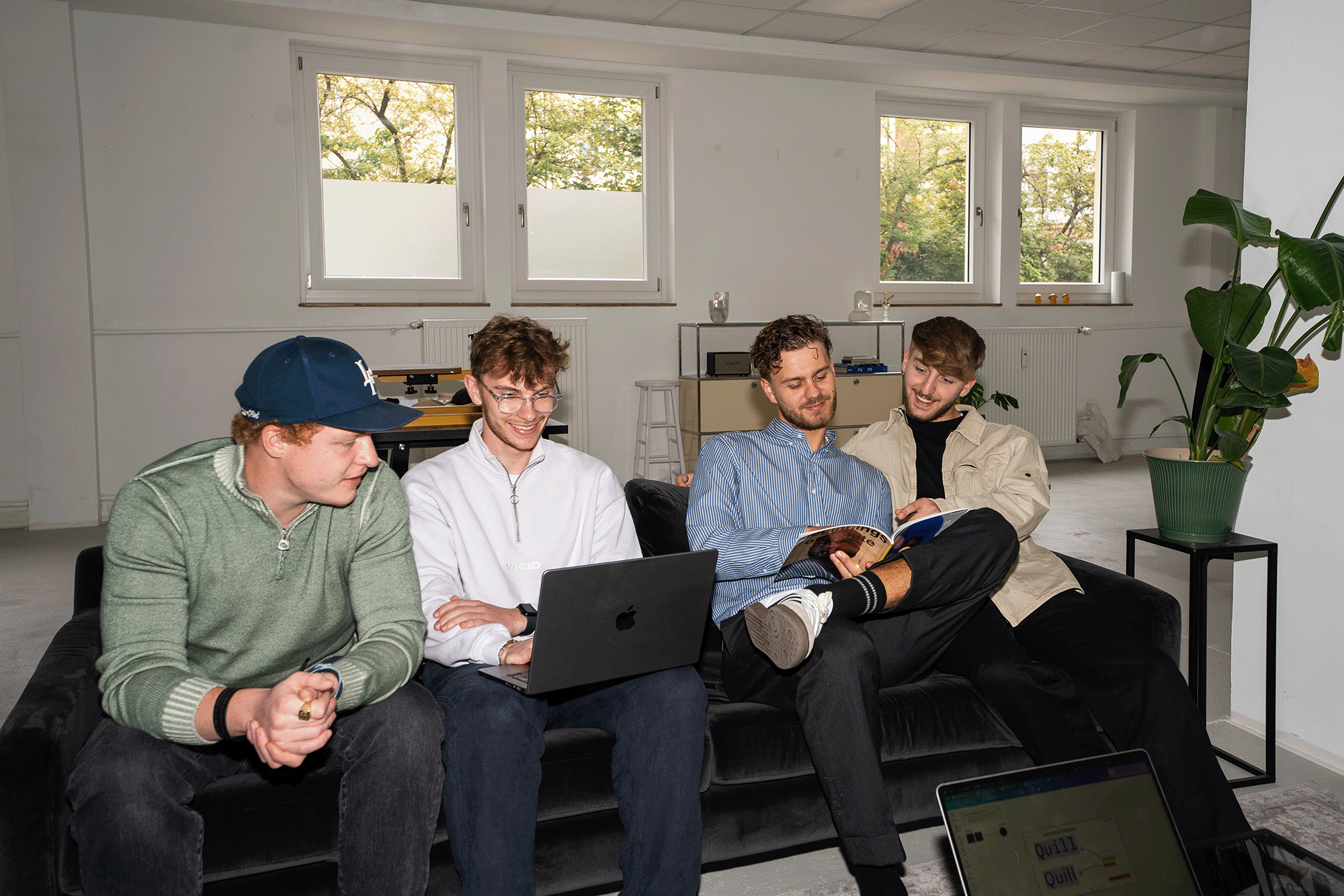 Vier Mitglieder des LebenGut Teams arbeiten mit Laptop und Notizbuch auf dem Sofa im Büro