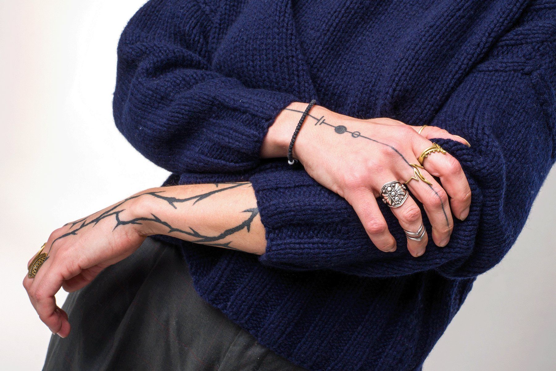 Detailaufnahme von Strickstruktur und Händen mit Ringen